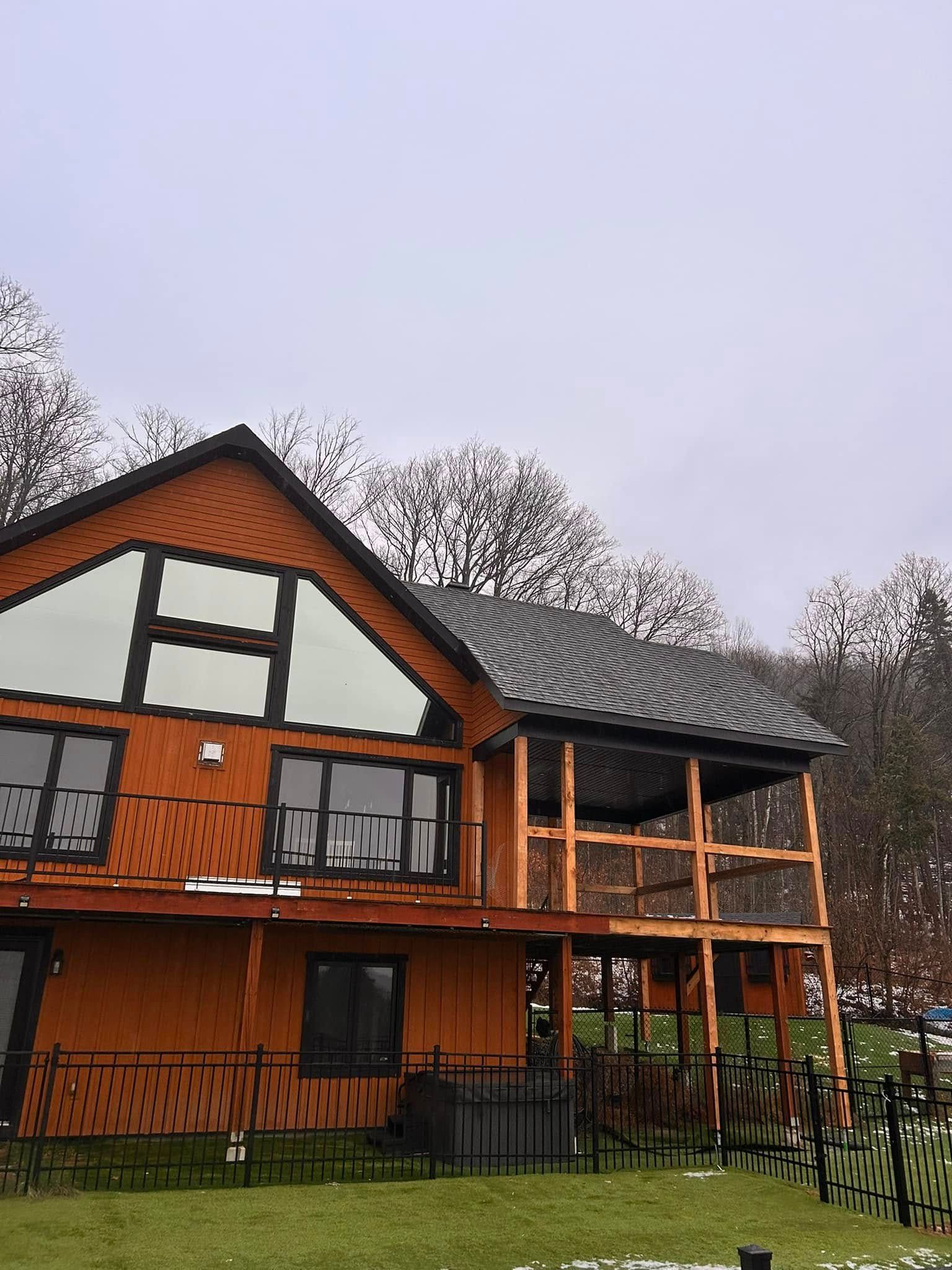 Une grande maison en bois avec un balcon et une clôture devant
