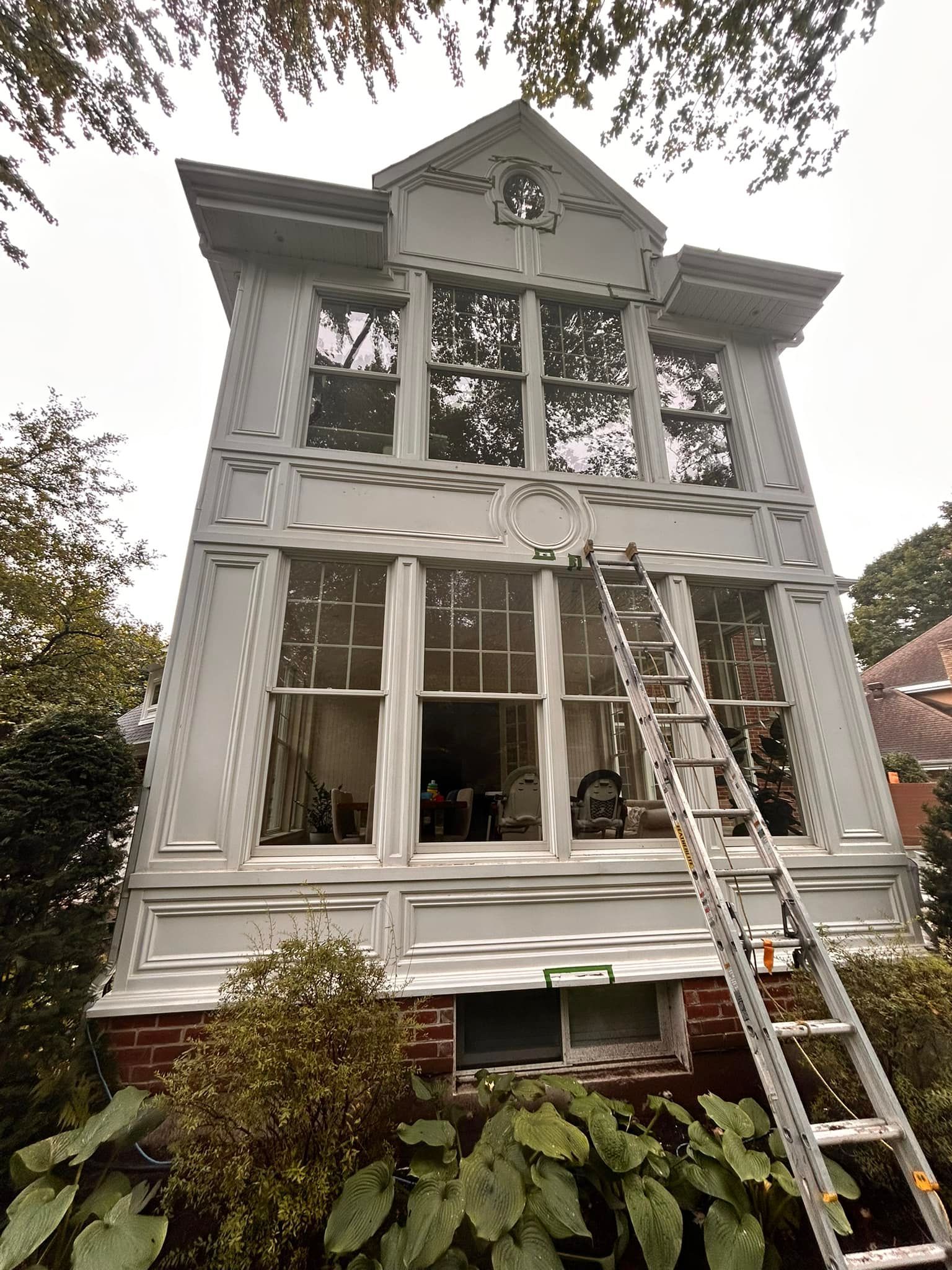 Une grande maison blanche avec une échelle sur le côté.