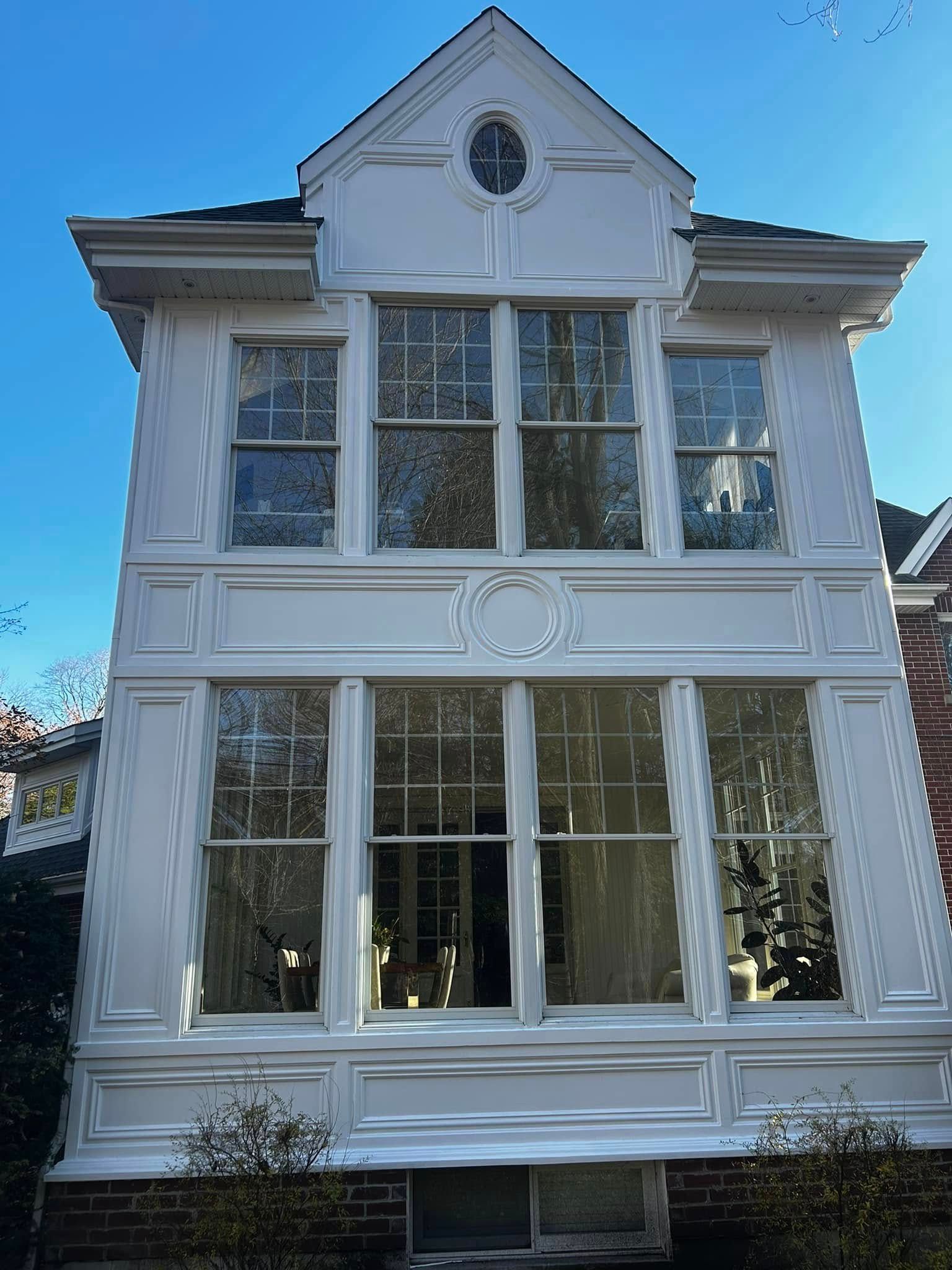 Une maison blanche avec beaucoup de fenêtres et un ciel bleu en arrière-plan