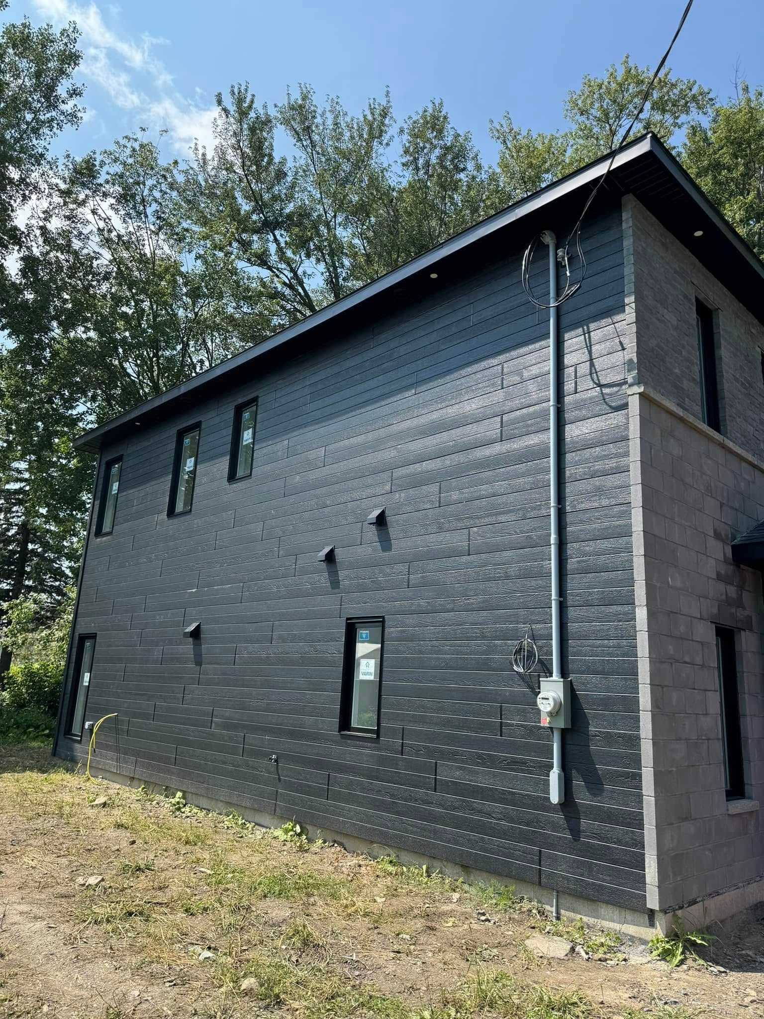 Un bâtiment en briques noires avec beaucoup de fenêtres est situé au sommet d'une colline.