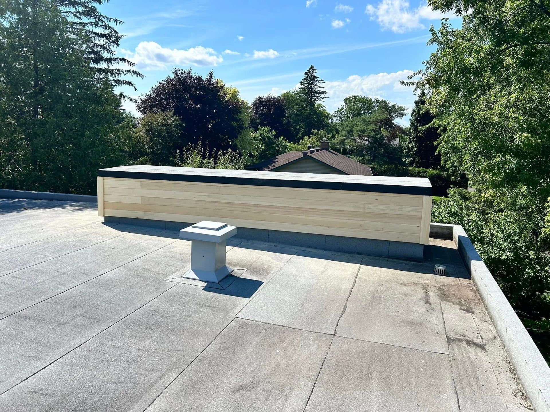 Un toit avec une cheminée dessus et des arbres en arrière-plan