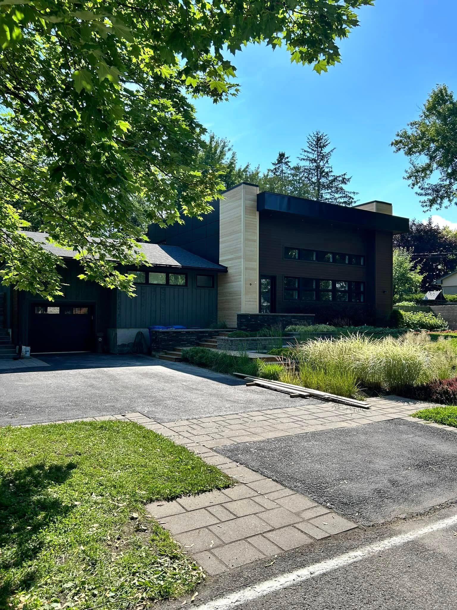 Une grande maison avec une allée qui y mène est entourée d'arbres et d'herbe.