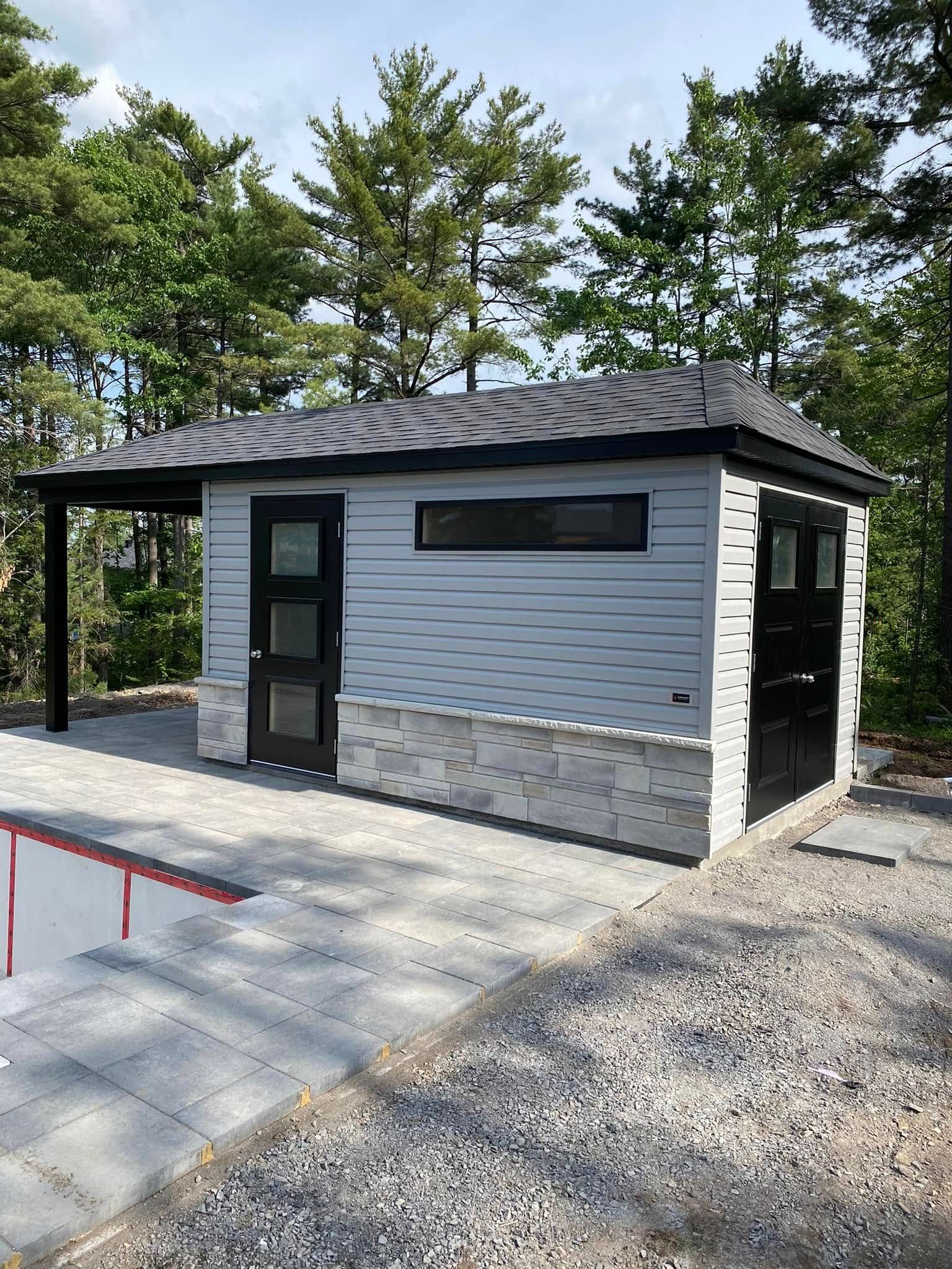 Un petit bâtiment blanc avec une porte noire se trouve à côté d'une piscine.