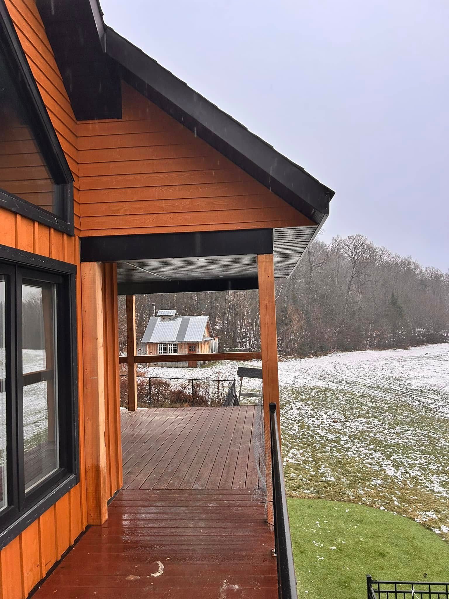 Une maison avec un porche et un champ enneigé en arrière-plan