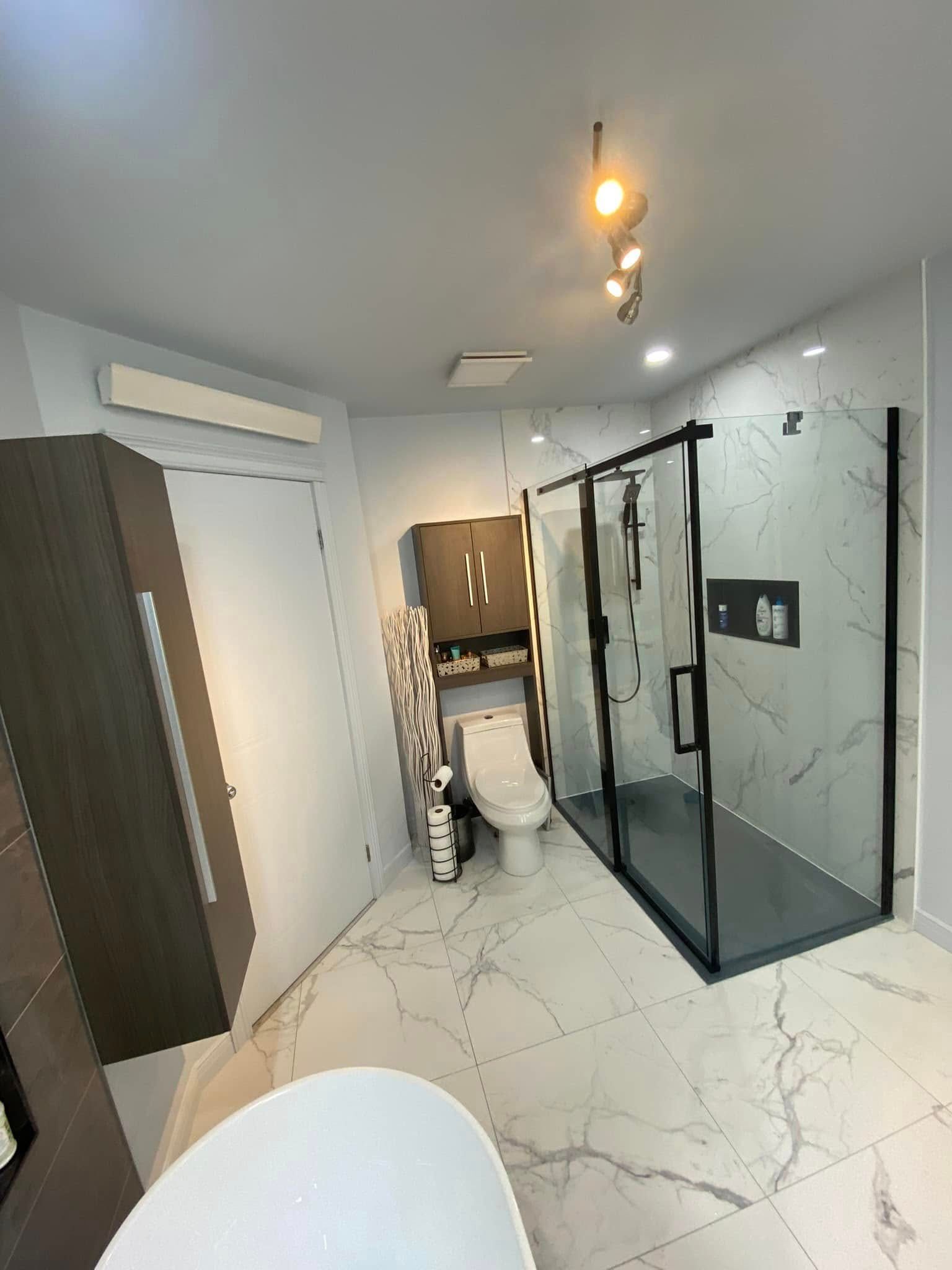 Salle de bain moderne avec sol en marbre, douche en verre, toilettes et armoires en bois foncé.