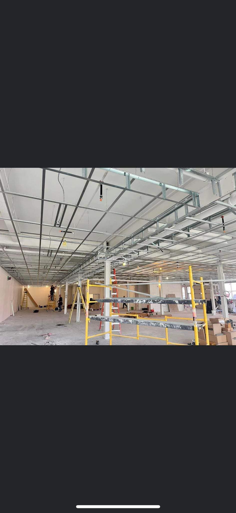 Construction intérieure d'un bâtiment. Échafaudages, supports de plafond et matériaux visibles.