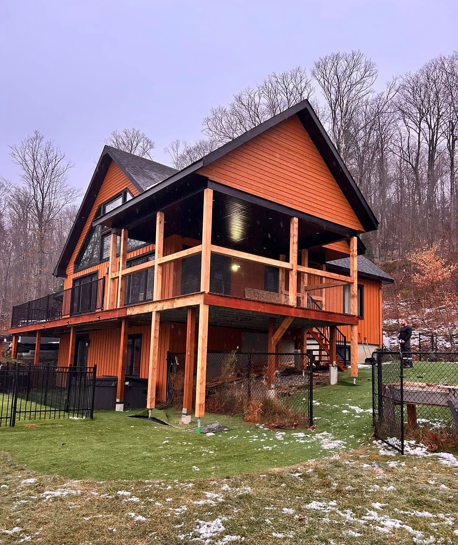 Une grande maison orange avec une grande terrasse au milieu d'un champ herbeux.