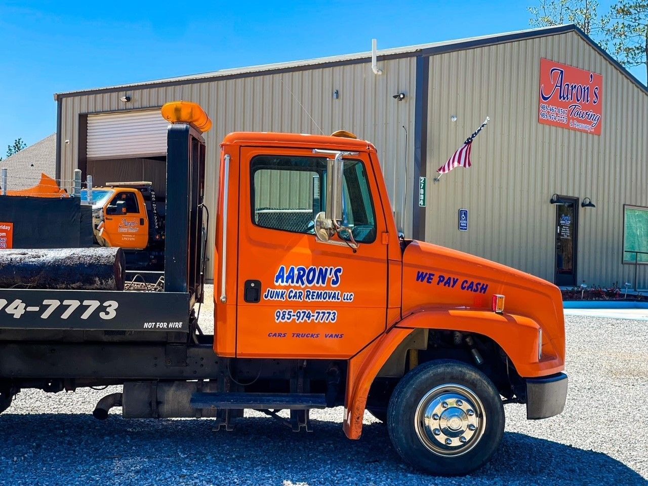 A picture of an orange tow truck in front of a tan building in Ponchatoula, LA