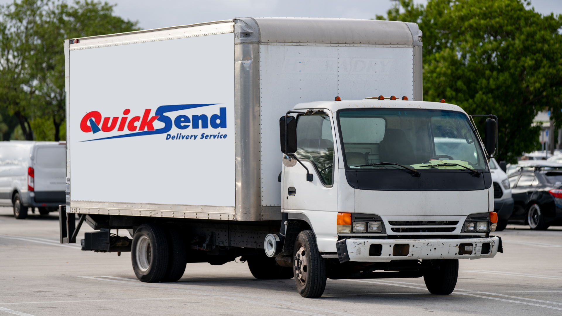A white truck with the word quicksend on the side is parked in a parking lot.