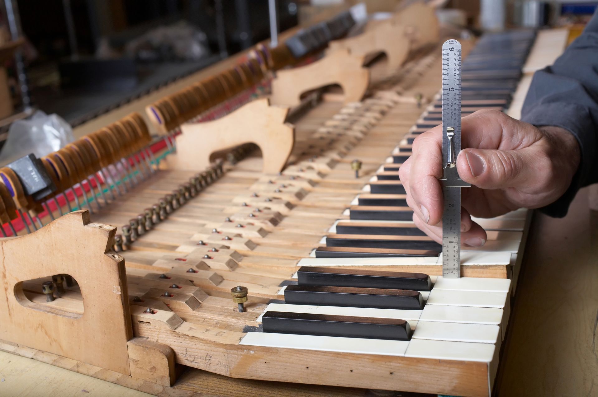 A person is measuring a piano keyboard with a ruler.