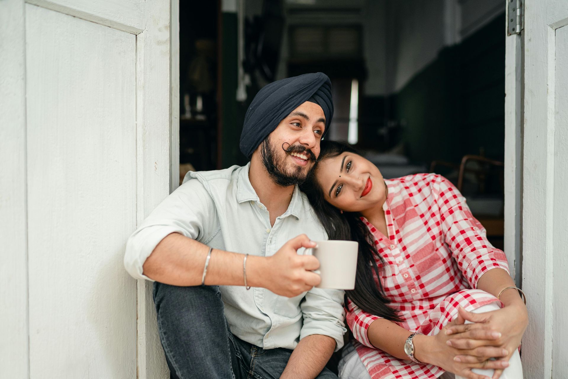 A man and a woman are sitting on the floor holding cups of coffee.
