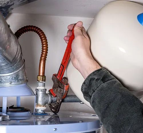Man works on a hot water heater with a pipe wrench — Hot Water Systems in South West Rocks, NSW