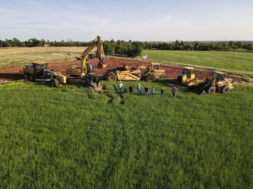 An aerial view of a construction site with a group of people standing in the middle of a field.