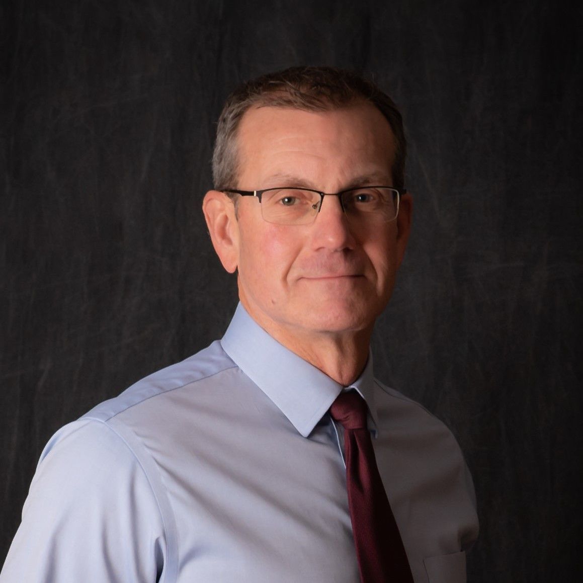 A man wearing glasses and a blue shirt and tie