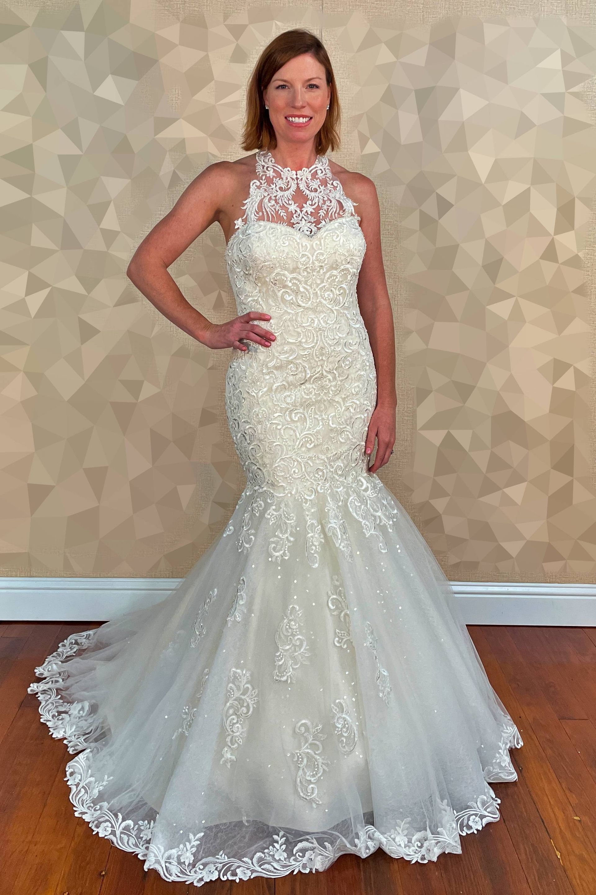 Woman in a beaded white wedding gown with a halter neckline and mermaid silhouette, smiling.