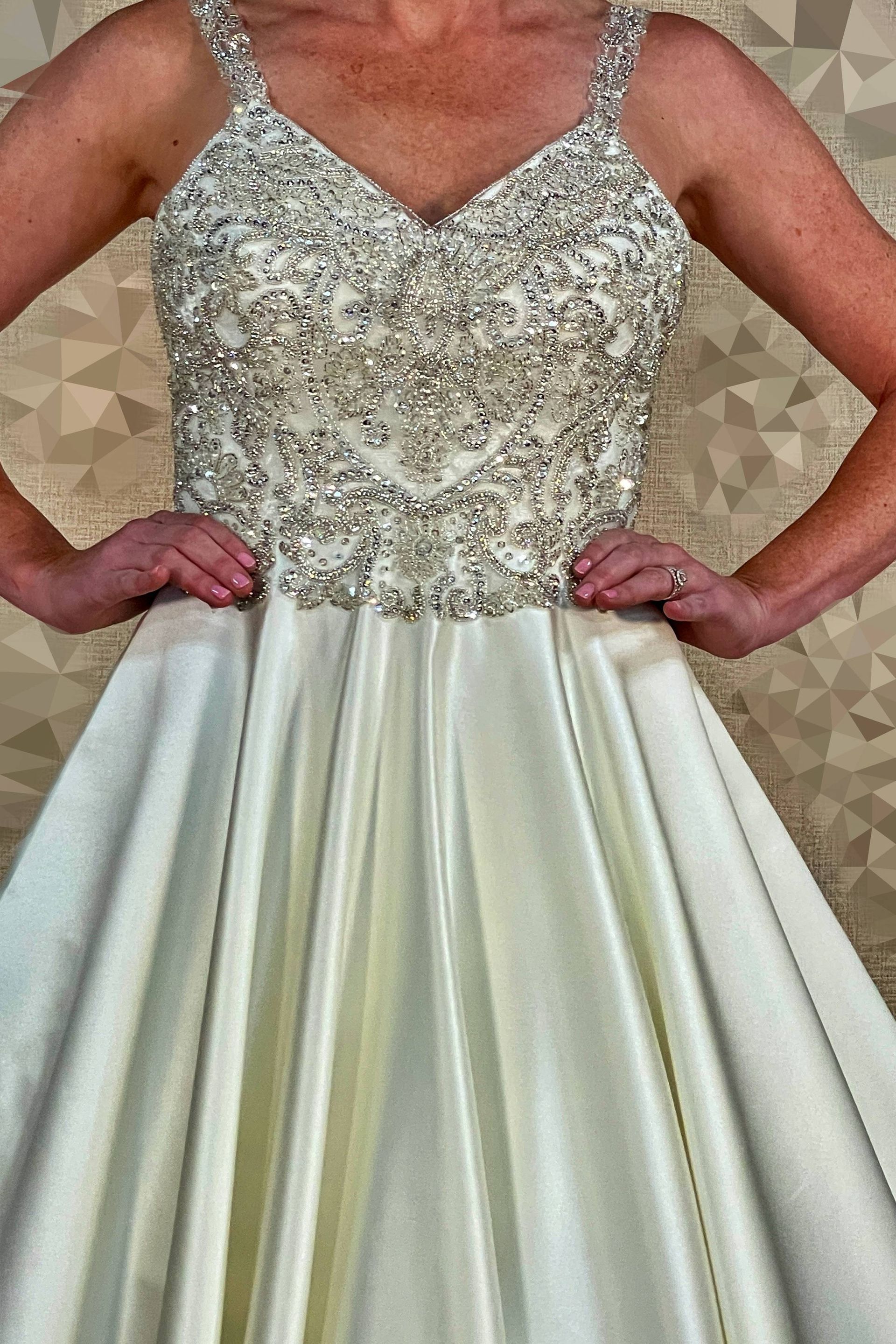 Woman in embellished bodice, satin ball gown. Hands on hips.