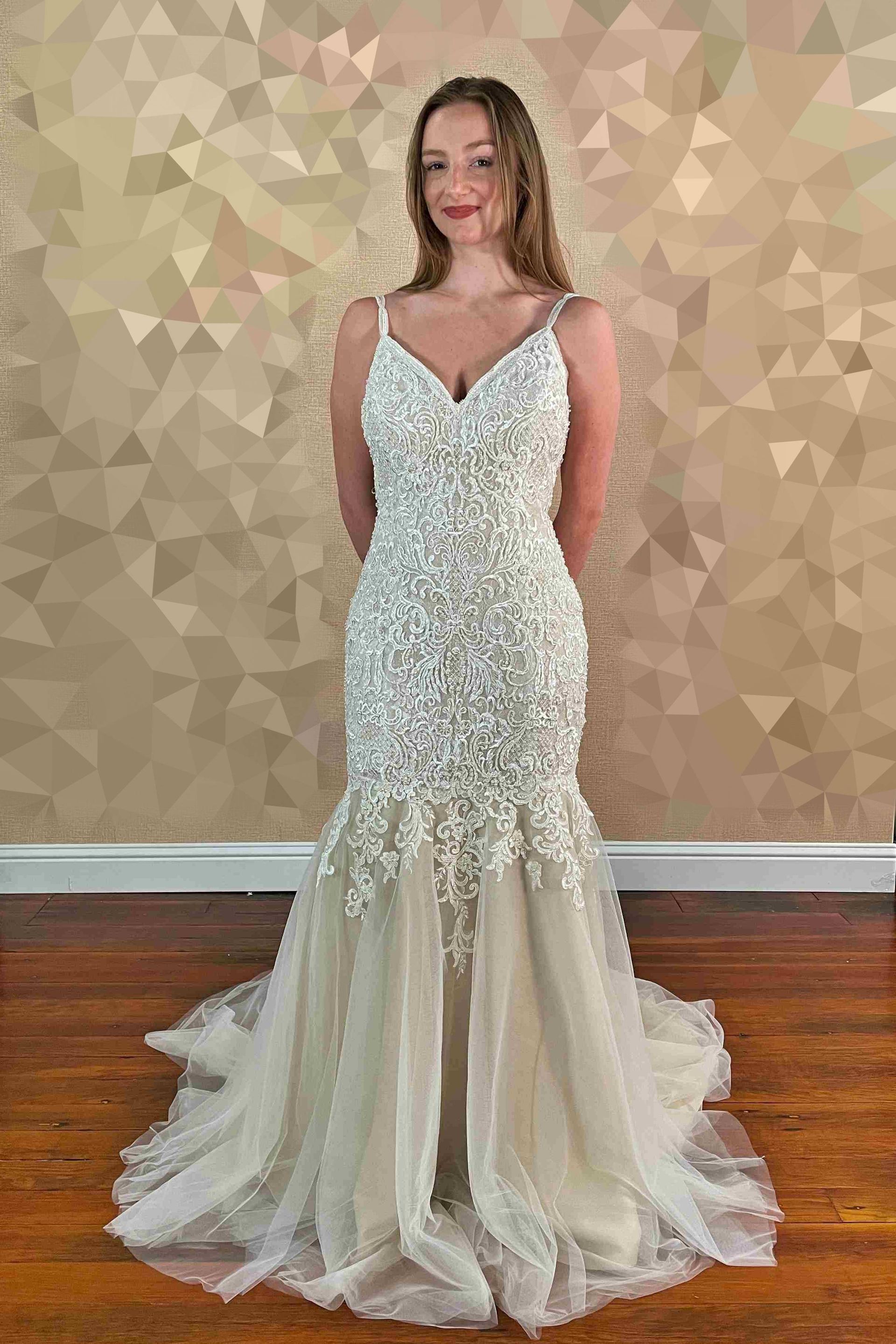 Woman in a beaded mermaid wedding dress stands in a room.