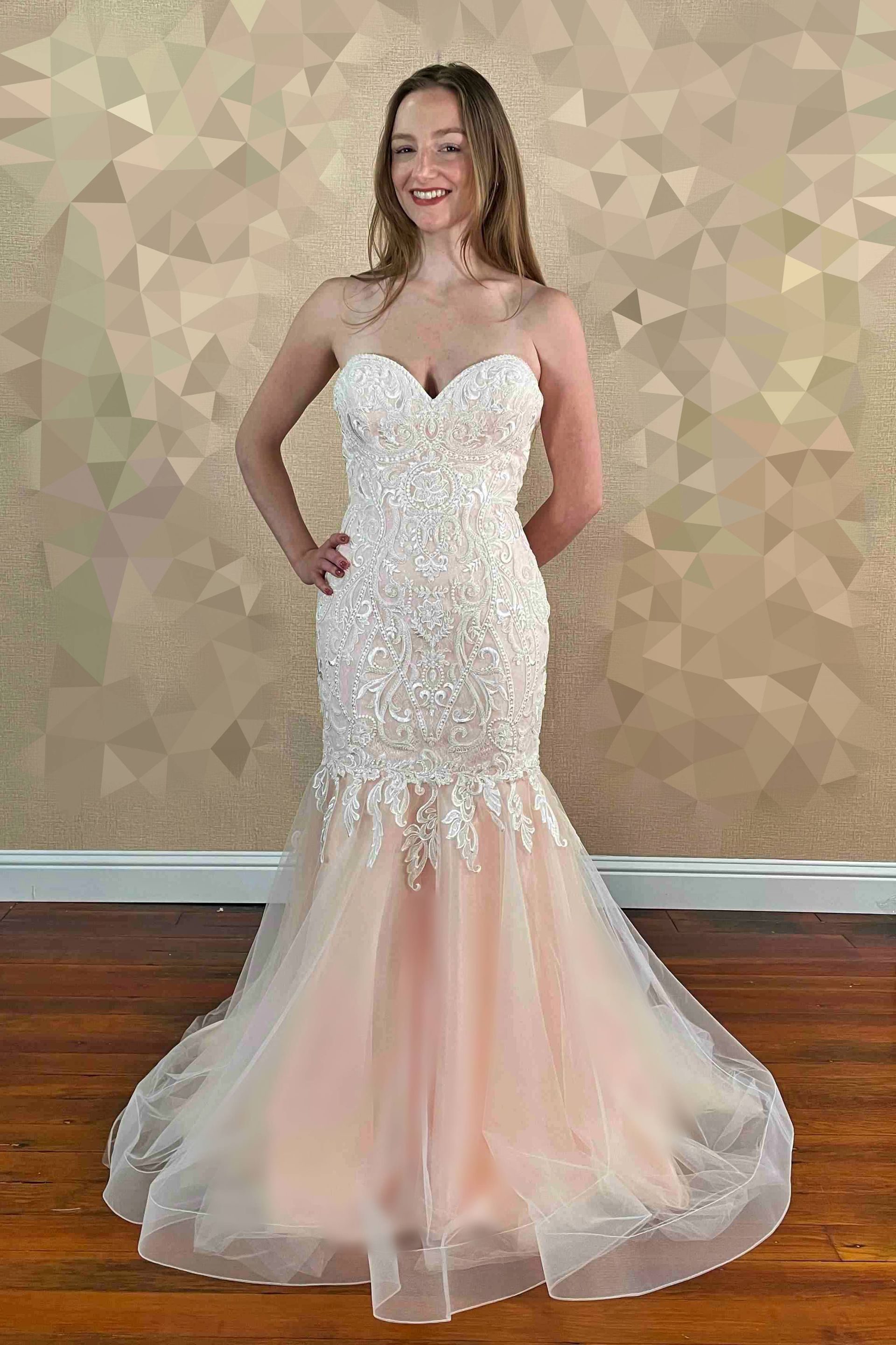 Woman in a strapless formal dress with a beaded bodice and peach-colored tulle skirt, posing.