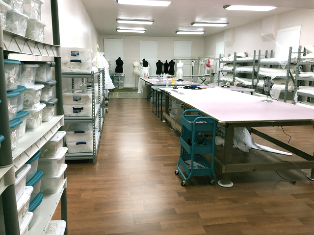 A costume shop interior with work tables, storage shelves, and mannequins.