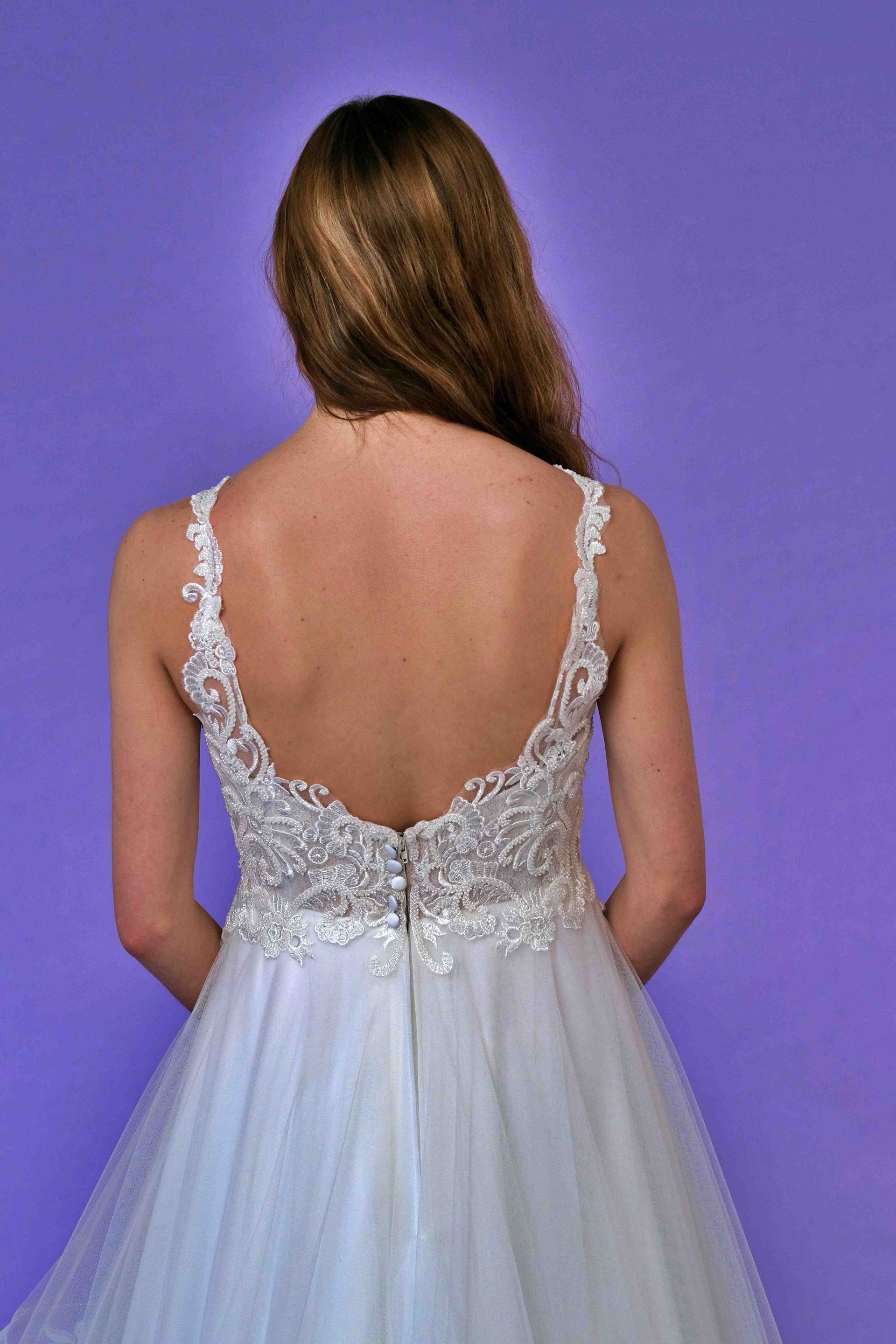 Woman in a wedding dress, back view; low back with beaded lace, flowing tulle skirt.