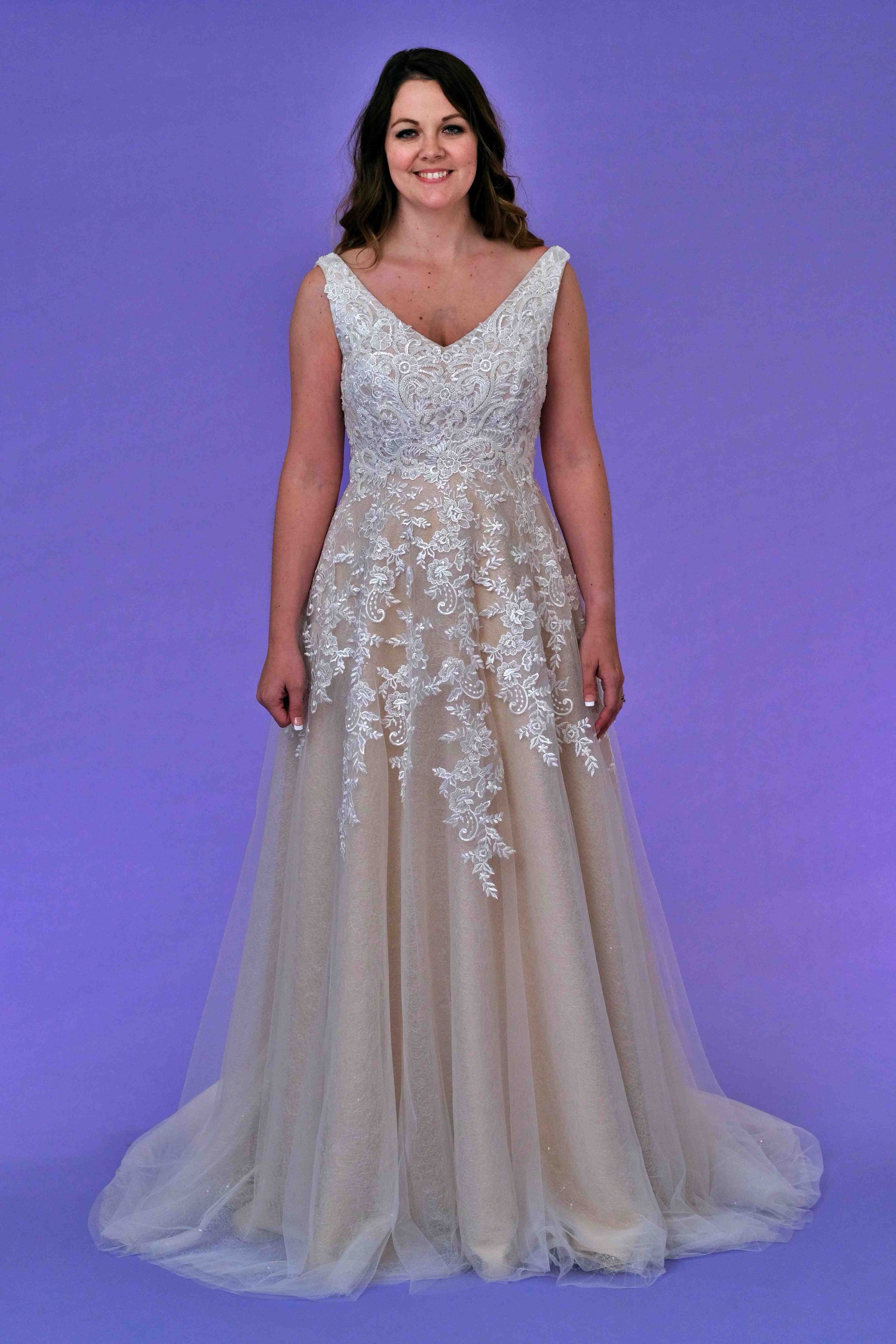 Woman in formal dress, smiling. The dress has a beaded bodice and light skirt against a lavender backdrop.