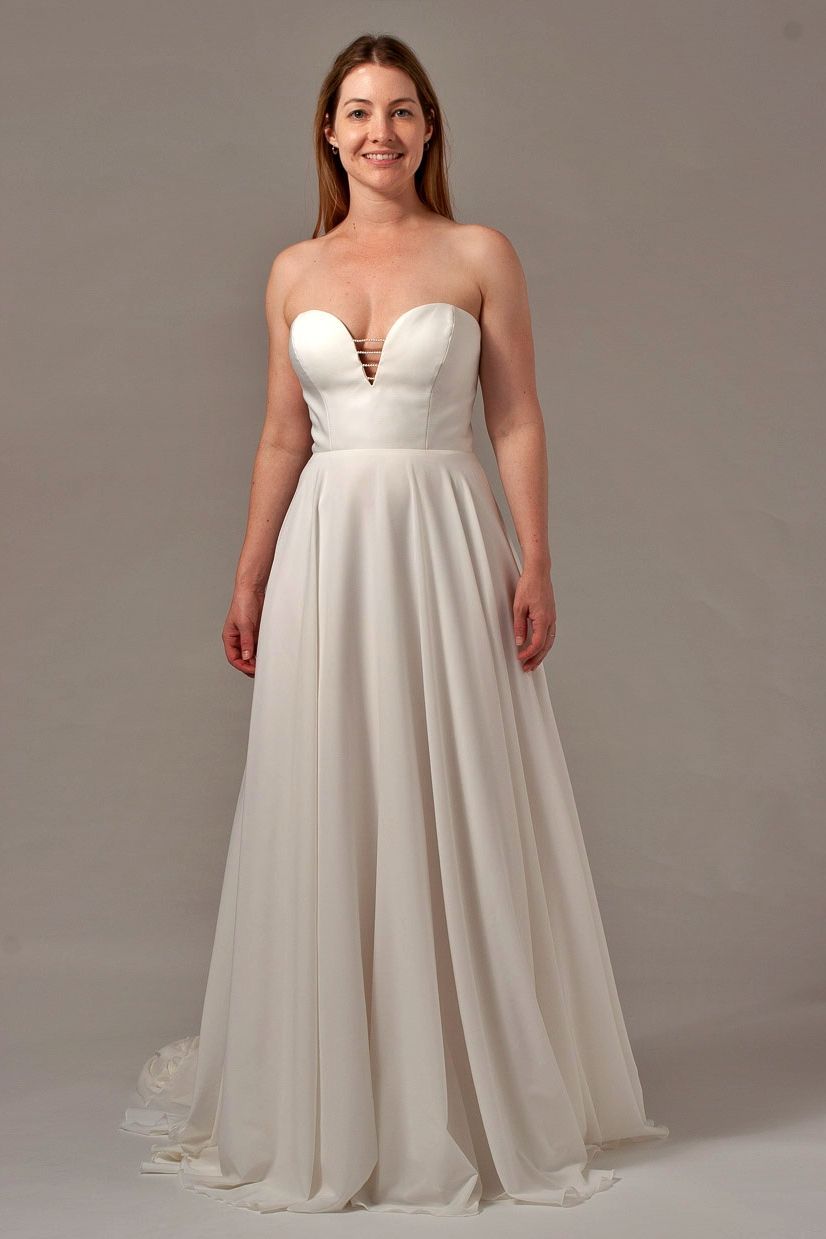 Woman in a white strapless wedding dress, smiling.