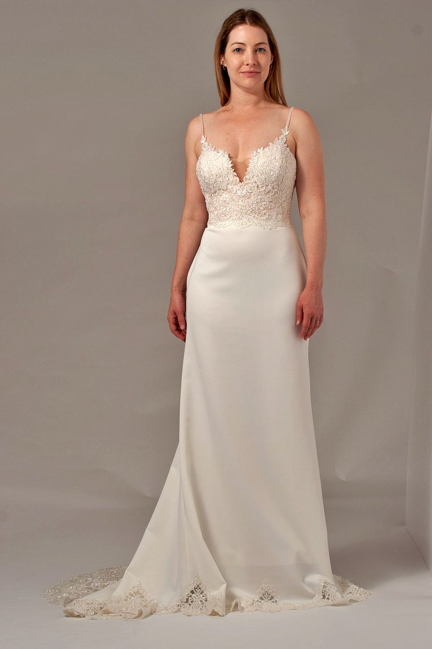 Woman wearing a white wedding dress with lace bodice, thin straps, and train.