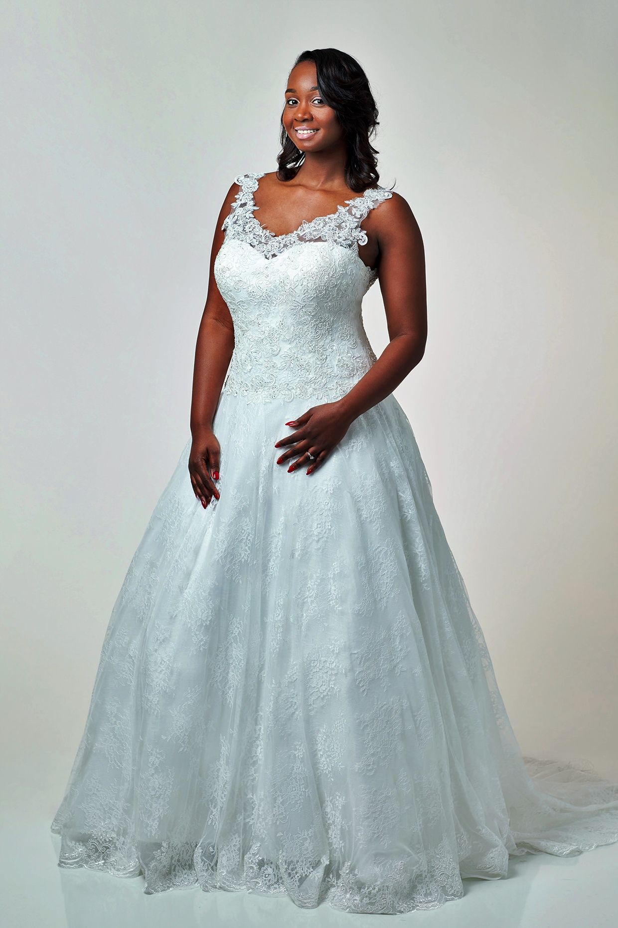 Woman in white wedding dress, smiling, hands on dress.
