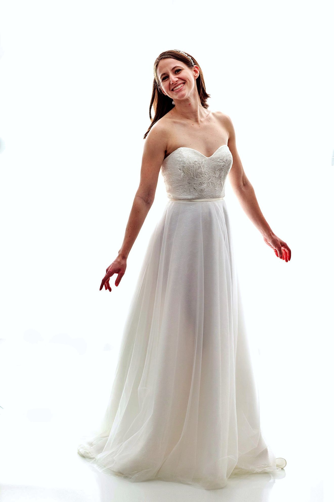 Woman in a white strapless wedding dress, smiling.