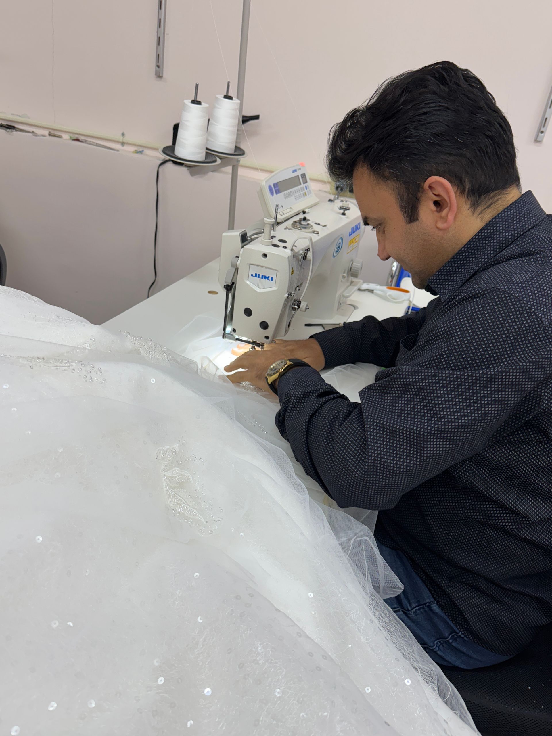 Row of wedding dresses hanging on a rack, various styles, mostly white, some with lace and beading.