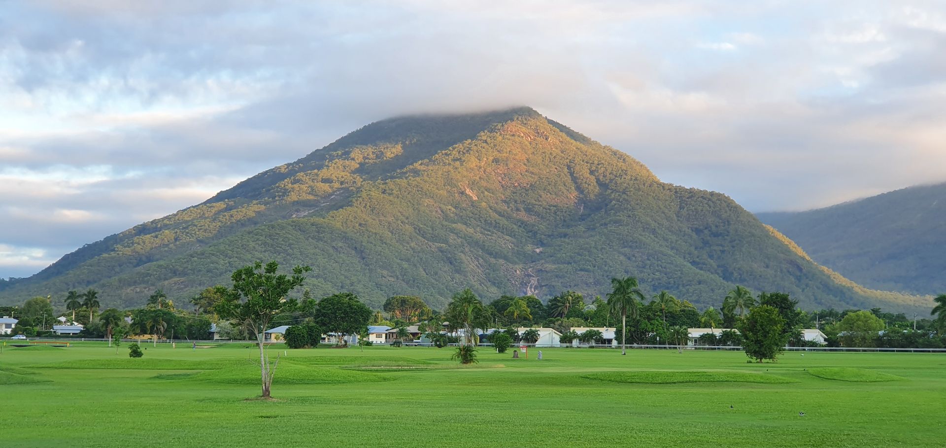 Green grass, mountain and cloudy skies— Rhino Excavator & Bobcat Hire in Gordonvale, QLD