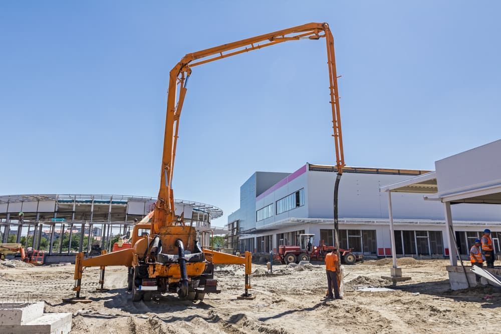 Orange Concrete Pump Truck at a Construction Site, With Extended Boom — Rhino Excavator & Bobcat Hire in Trinity Beach, QLD