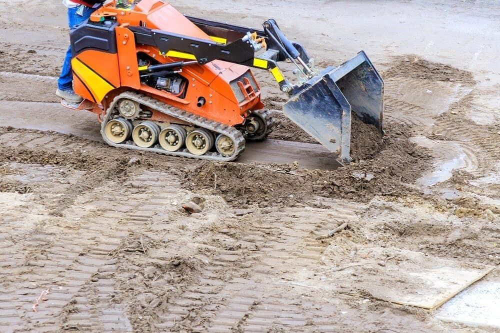 Orange Mini-excavator With Operator, Scooping Dirt on a Construction Site — Rhino Excavator & Bobcat Hire in Brinsmead, QLD 