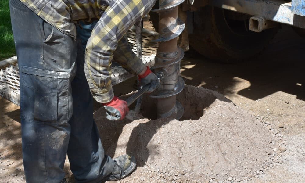 Man Operating a Drill, Creating a Hole in the Ground — Rhino Excavator & Bobcat Hire in Trinity Beach, QLD