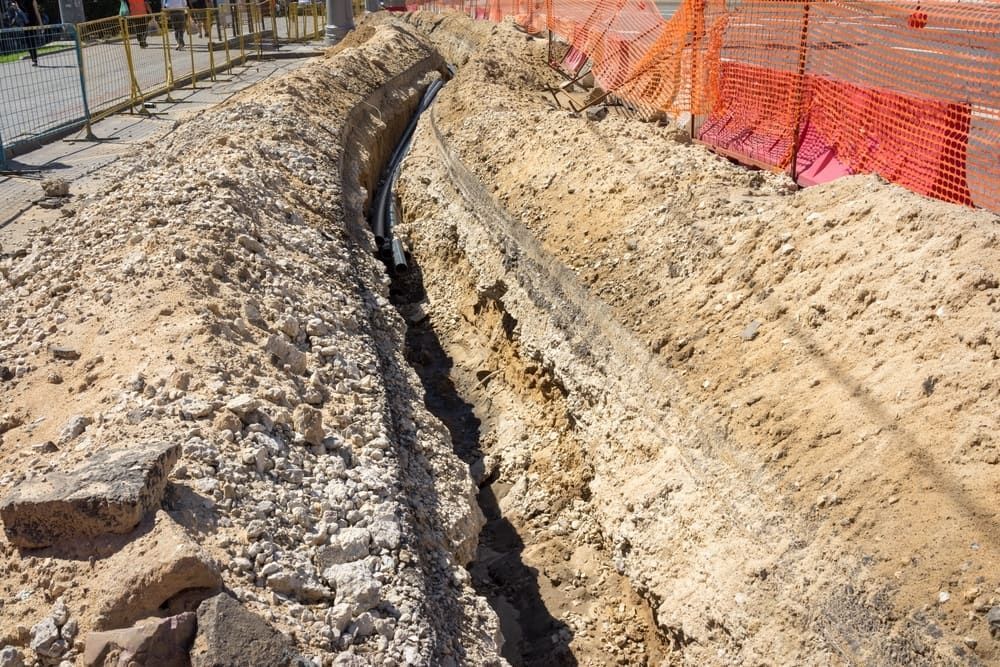 Construction Site Trench With Dark Cable Running Through It — Rhino Excavator & Bobcat Hire in Whitfield, QLD