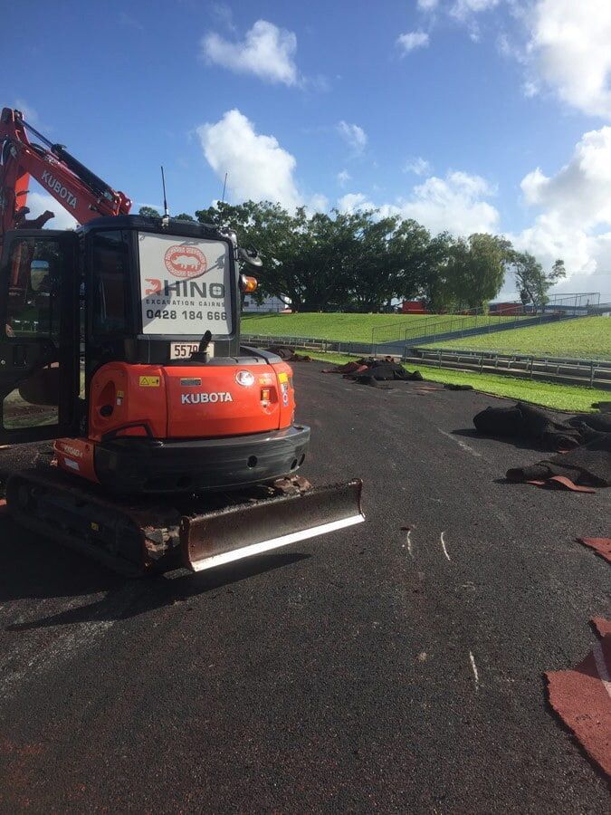 Orange Excavator on Dark Asphalt, Trees in the Background — Rhino Excavator & Bobcat Hire in Trinity Beach, QLD