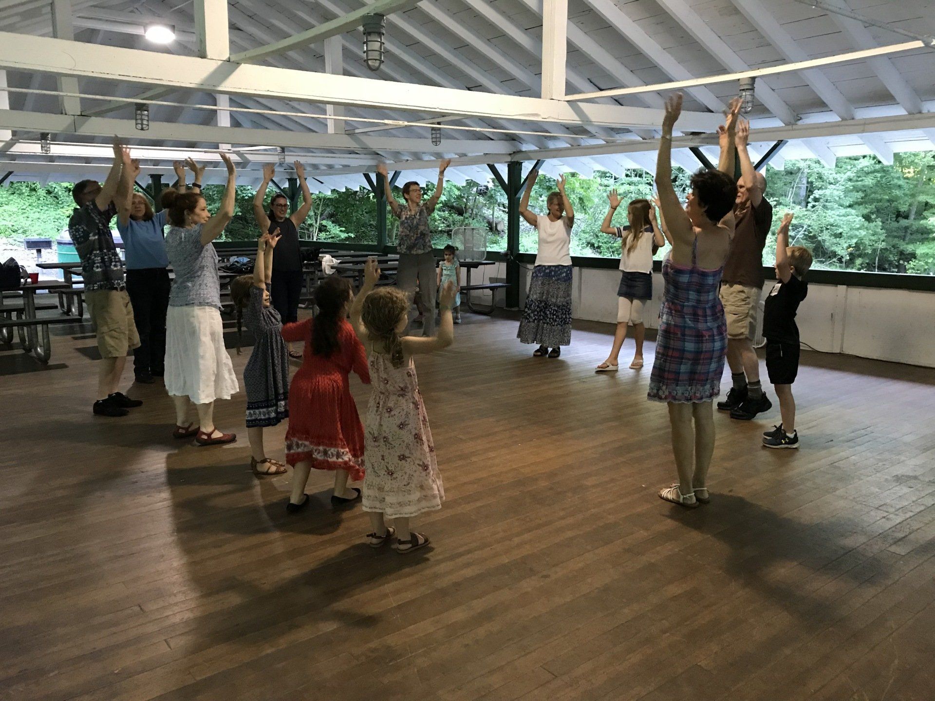 A group of people are dancing in a room with their arms in the air.