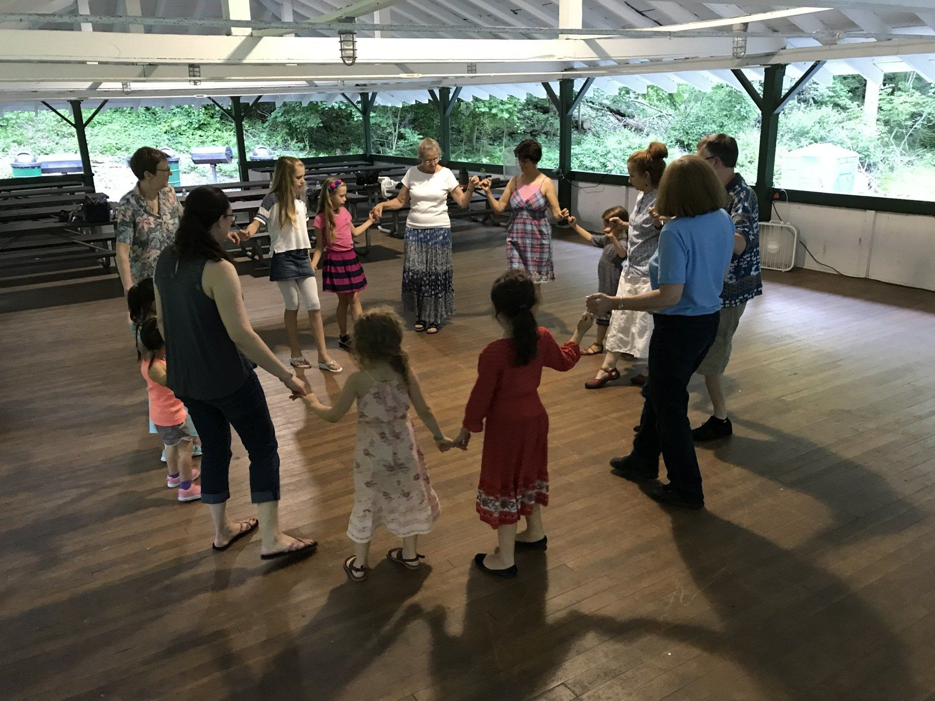 A group of people are dancing in a circle on a wooden floor.