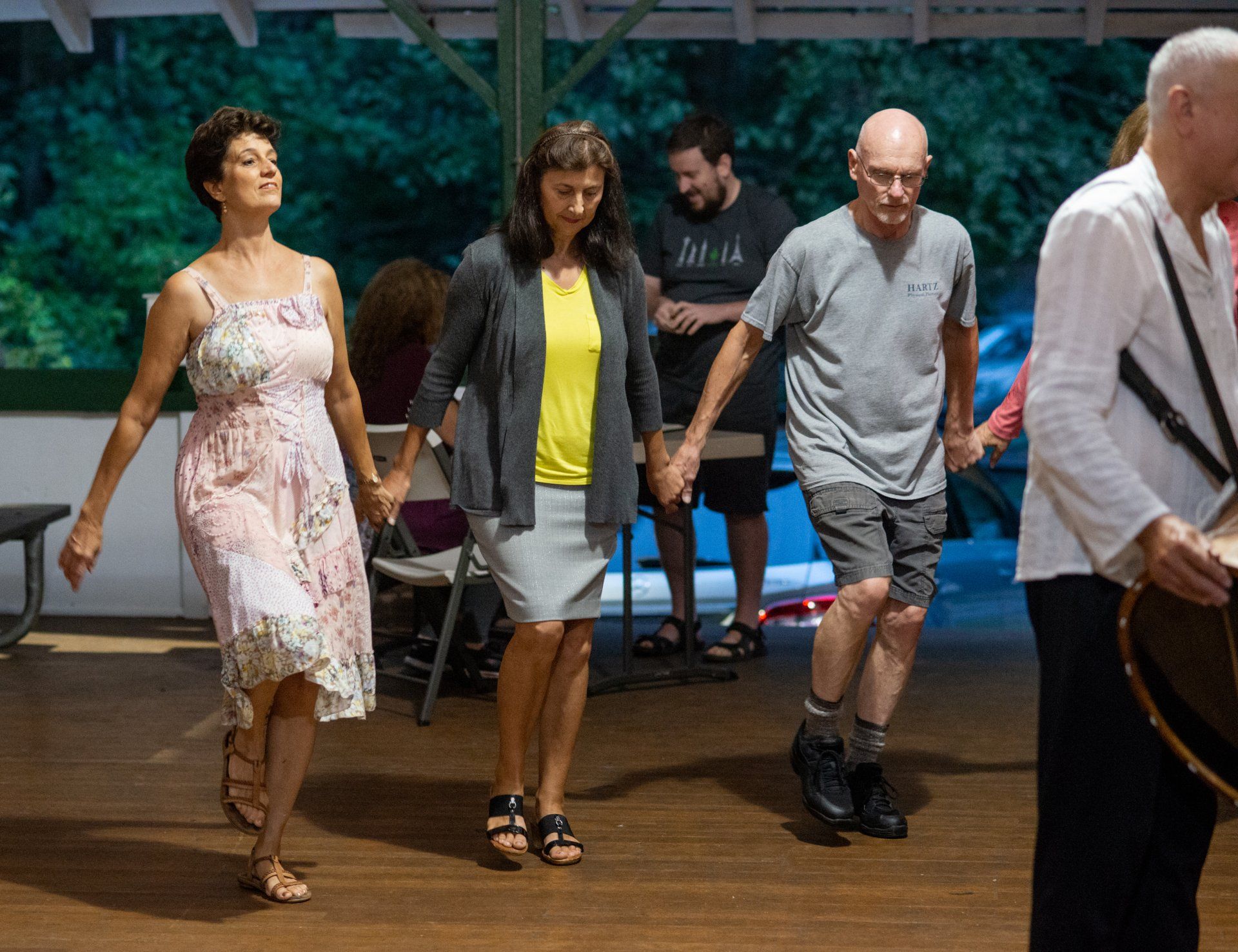 A group of people are dancing in a room while a man plays a guitar.