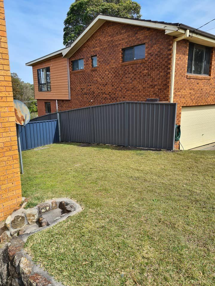 A Large Brick House with A Fence in Front of It — D & B Fencing in Taree, NSW