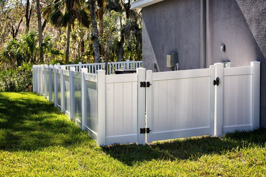 A White Fence with A Black Gate Is in The Backyard of A House — D & B Fencing in Taree, NSW