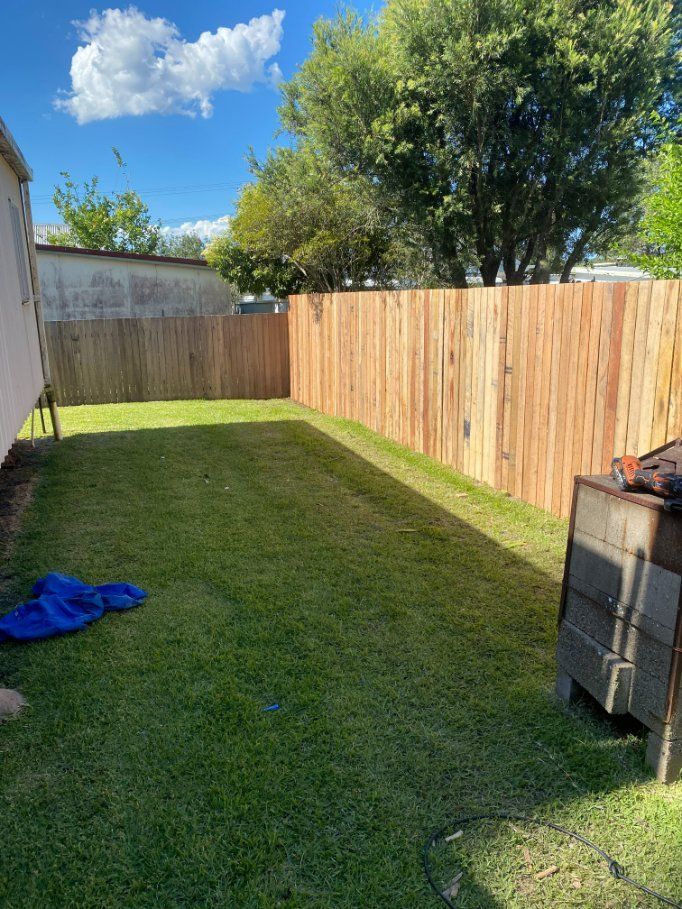 A Backyard with A Wooden Fence and A Lush Green Lawn — D & B Fencing in Taree, NSW