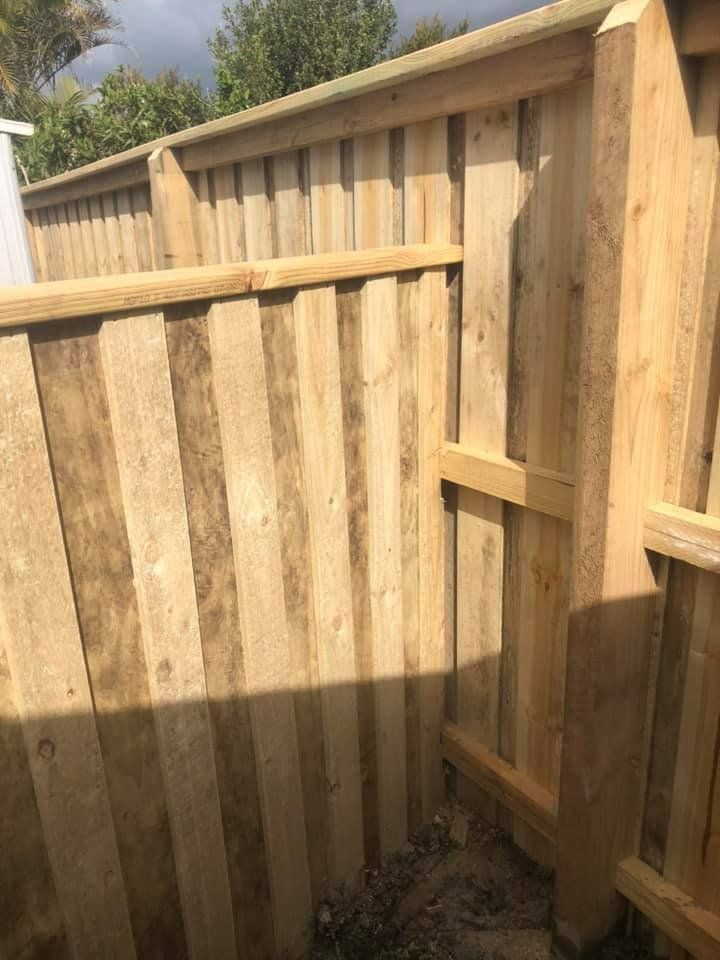 A Close up Of a Wooden Fence with Trees in The Background — D & B Fencing in Forster, NSW