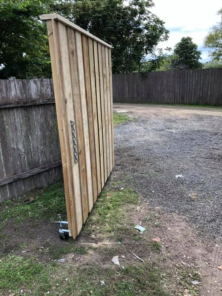 A Wooden Fence Is Sitting on The Side of A Dirt Road — D & B Fencing in Taree, NSW