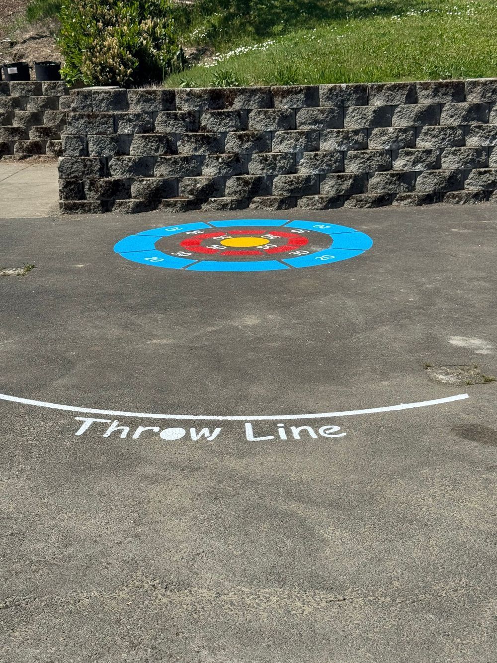 A throw line is painted on the ground in front of a stone wall.