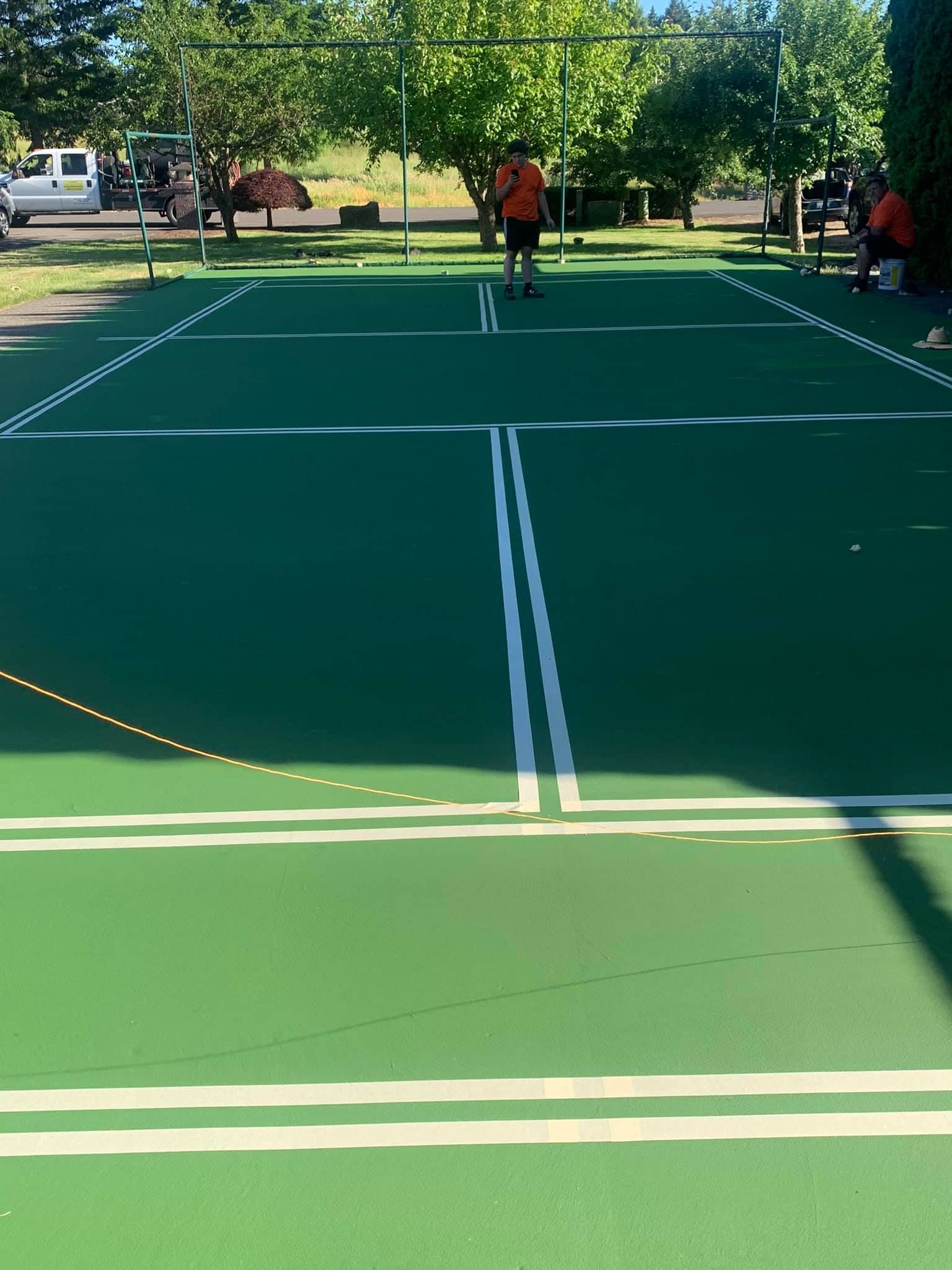 A group of people are playing tennis on a green court.