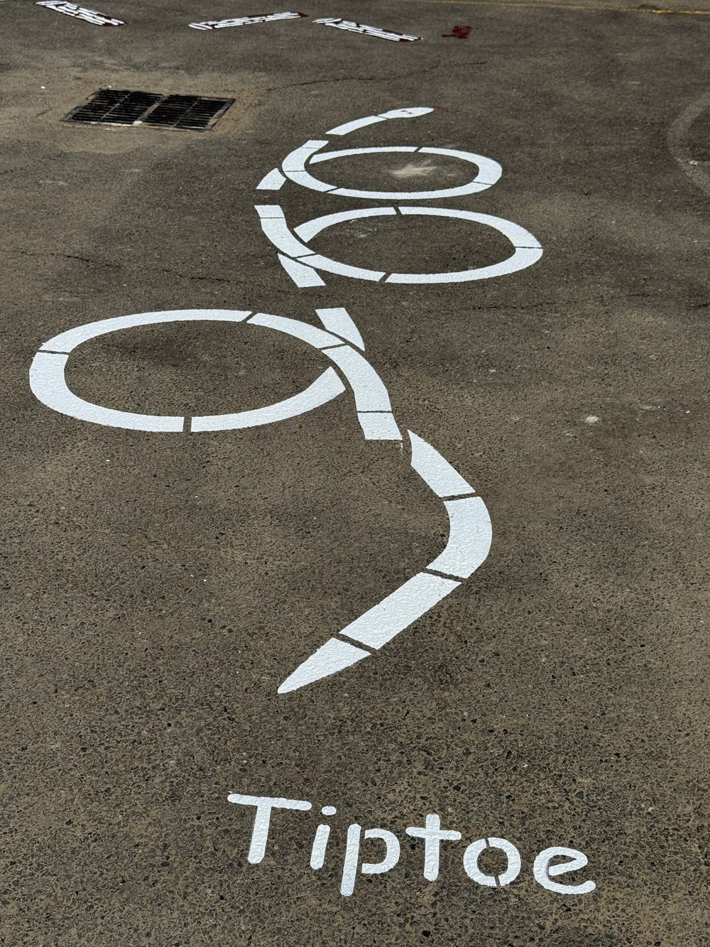 The word tiptoe is painted on the ground in white chalk.