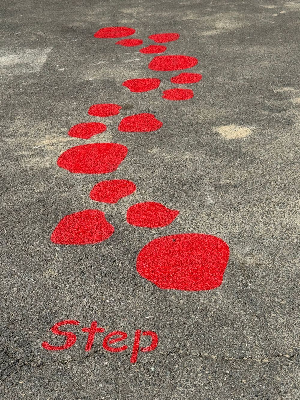 A row of red footprints on the ground with the word step written in red