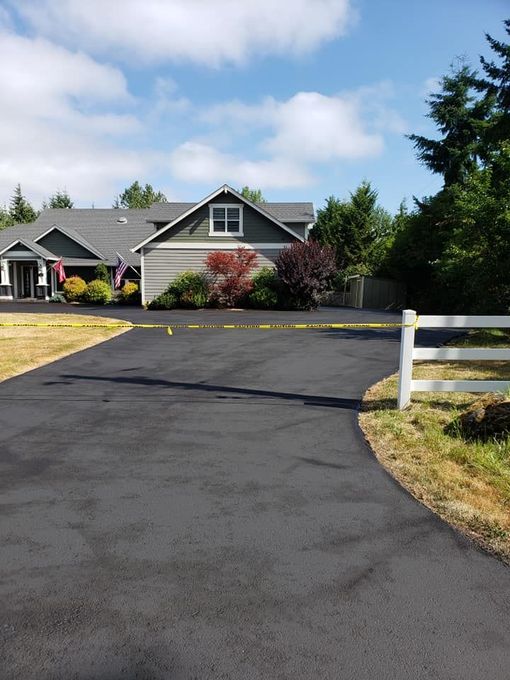 A driveway with flowers and trees on the side of it.