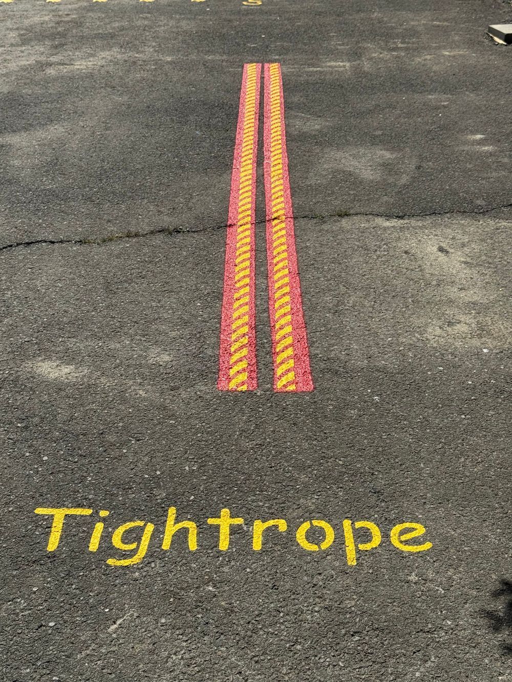 The word tightrope is painted on the side of a road.